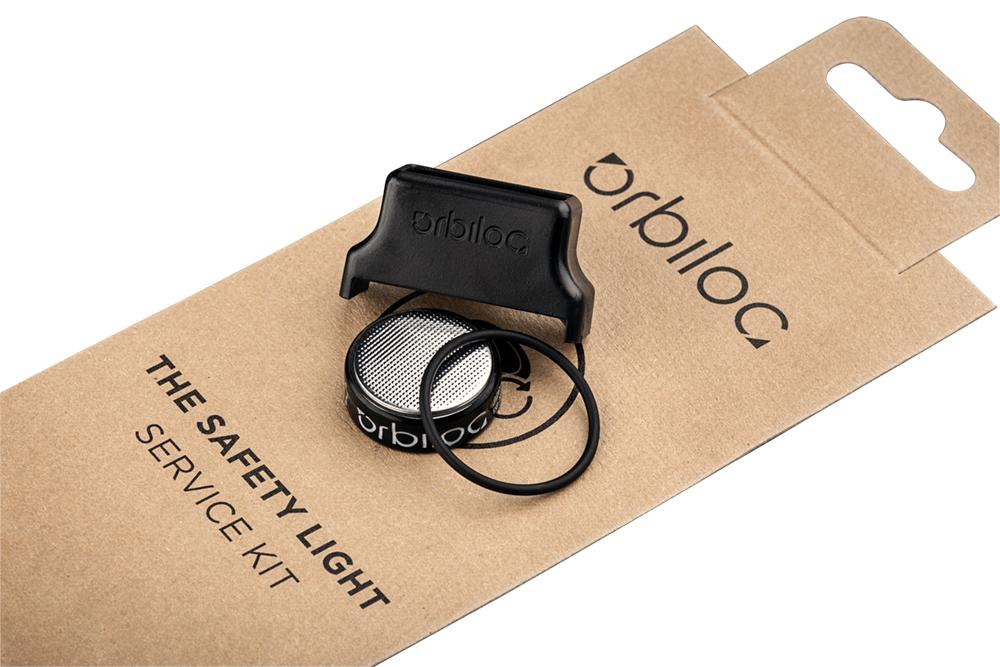 Orbiloc Service Kit für Sicherheitslicht, bestehend aus Batterien, Dichtungsring und Verschlusswerkzeug auf brauner Verpackung mit Produktaufdruck.